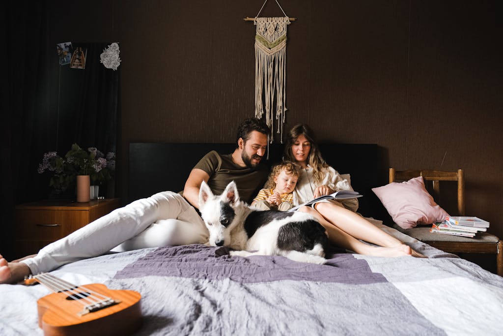 New Pet Parent Mistakes- A family enjoys reading together with their pet dog in a cozy bedroom setting.