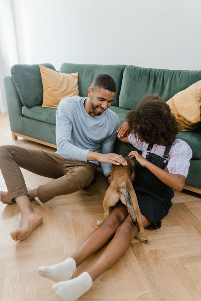 A joyful moment as a man and girl bond with their pet dog indoors.